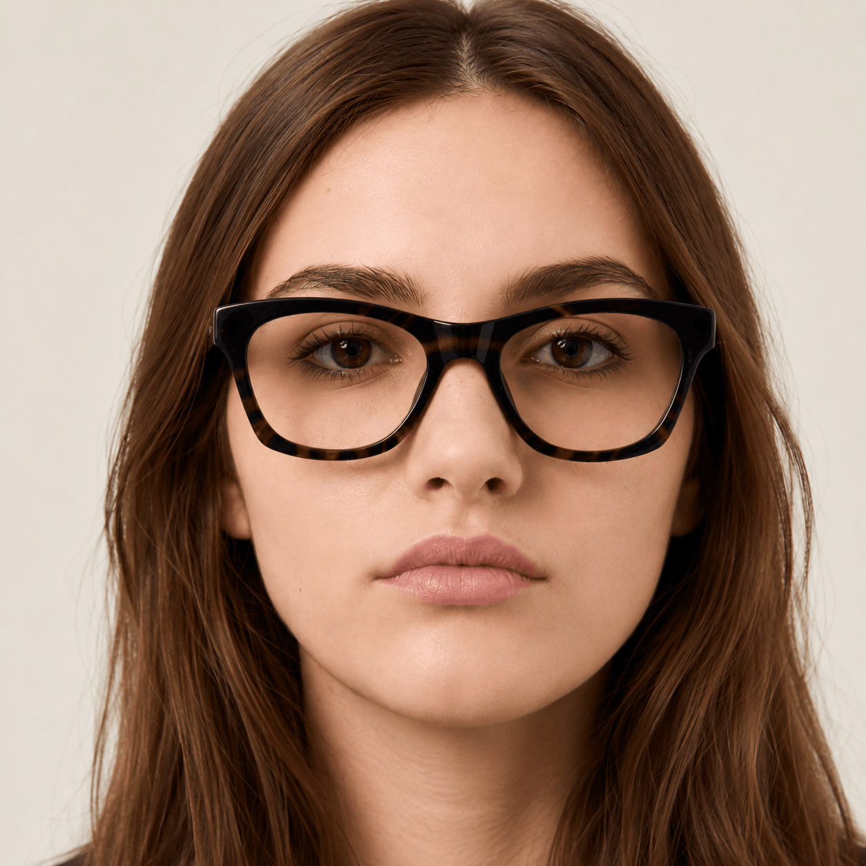 Woman wearing black glasses and a navy blazer against a beige background